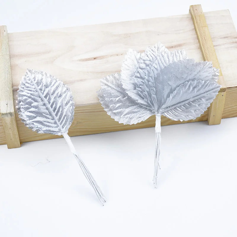 A set of twelve silver silk leaf artificial plant stems with vases displayed on a wooden surface.
