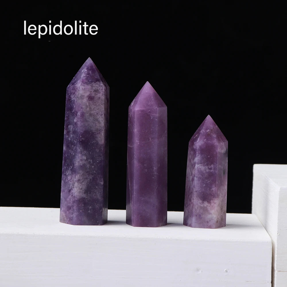 Three purple lepidolite crystal points standing upright on a white surface.