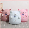 Three pink and white cartoon bear figures resembling pigs are displayed on a light surface.