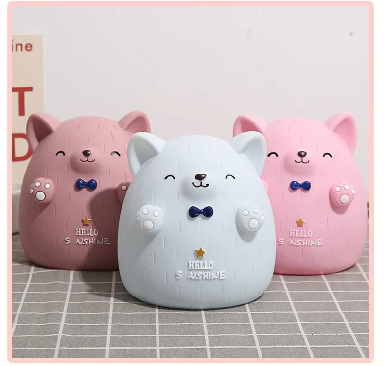 Three pink and white cartoon bear figures resembling pigs are displayed on a light surface.
