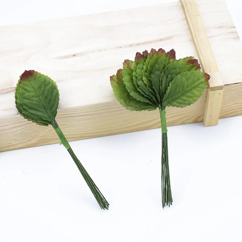 A set of twelve silk leaf artificial plant stems with vases displayed on a wooden surface.