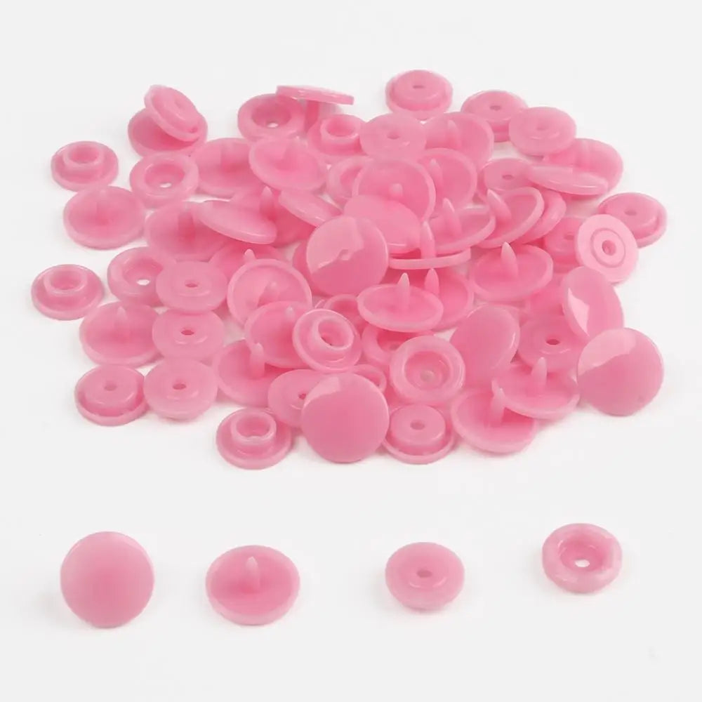 A pile of assorted pink snap buttons, measuring 12mm and 10.5mm, for crafting.