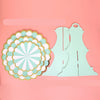 A light mint green cardboard cupcake stand with a decorative flower cutout on a pink background.