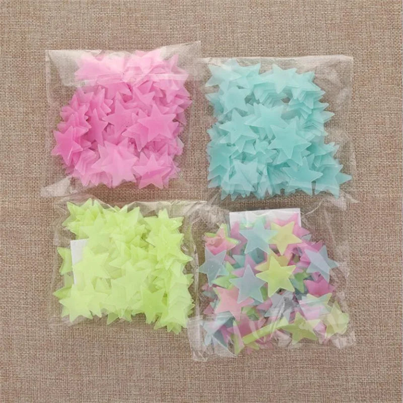 Three clear plastic bags filled with glow-in-the-dark star wall stickers in pink, light blue, and green.