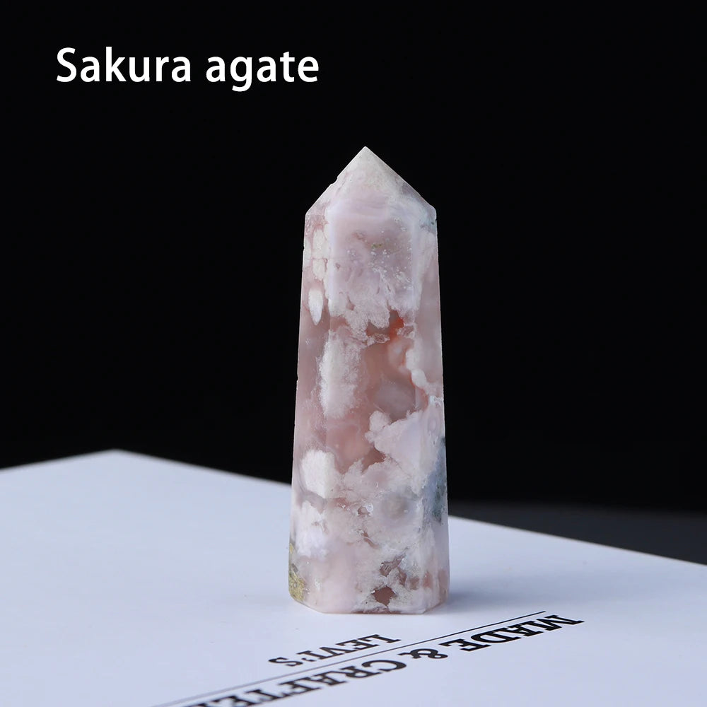 A clear pink sakura agate point prism tower displayed on a white surface.