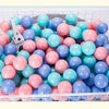 A white basket filled with a 50-pack of colorful, shiny, round balls in shades of pink, blue, and teal.