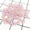 A pile of pink iridescent acrylic round beads for jewelry making scattered on a black and white grid.