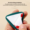 A hand holds a green suction cup towel holder with white triangular inserts, demonstrating no-hole wall installation.