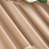 A close-up of a beige sheer chiffon fabric drape with a white rose and a glass candle holder.