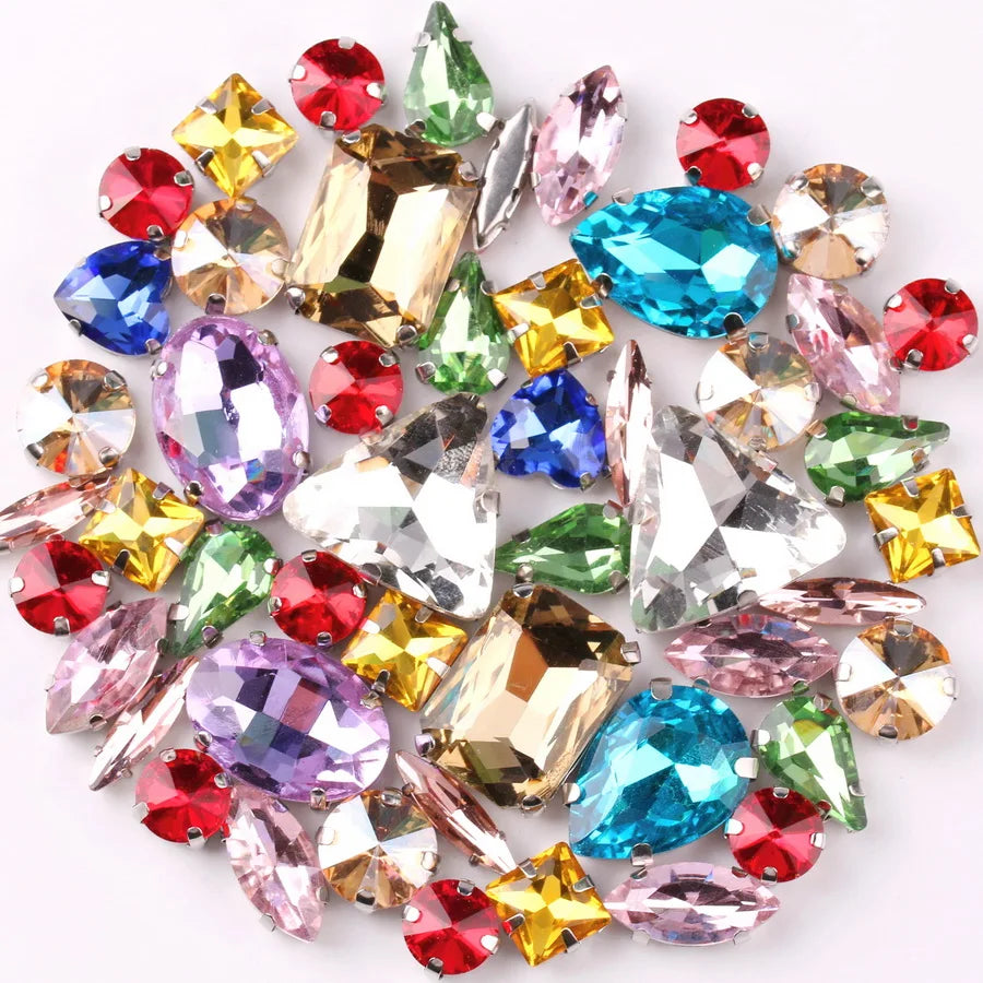 A mix of silver claw setting glass rhinestones in jelly candy AB colors scattered on a white background.