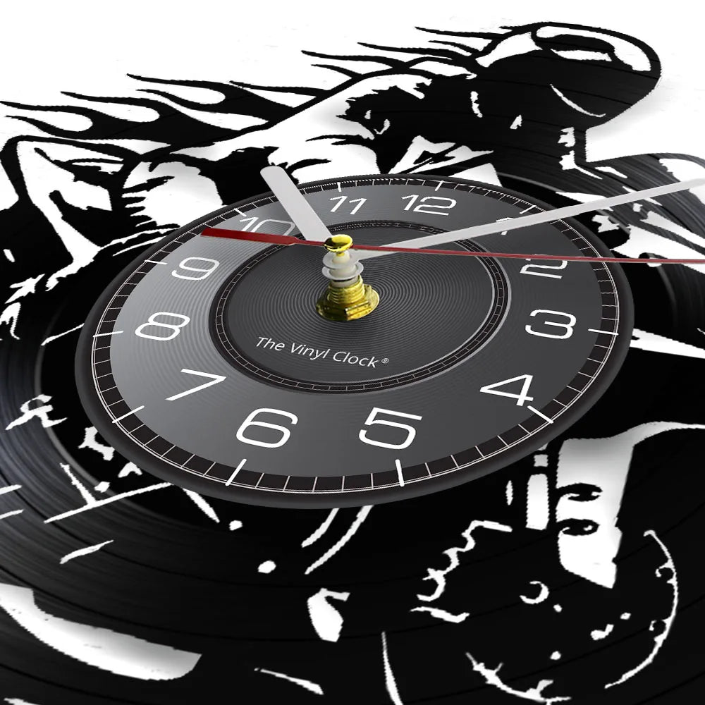 A black vinyl record wall clock with a gold-colored hand and face set against a background of motorcycle rider silhouettes.