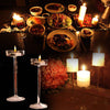 A dark table setting features multiple glass candle holders and various dishes, creating an elegant ambiance.