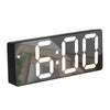 A black digital alarm clock displaying the time 6:00 on a wooden surface.