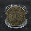 Moneda de metal dorada redonda con la palabra SÍ grabada, en un soporte de plástico transparente.