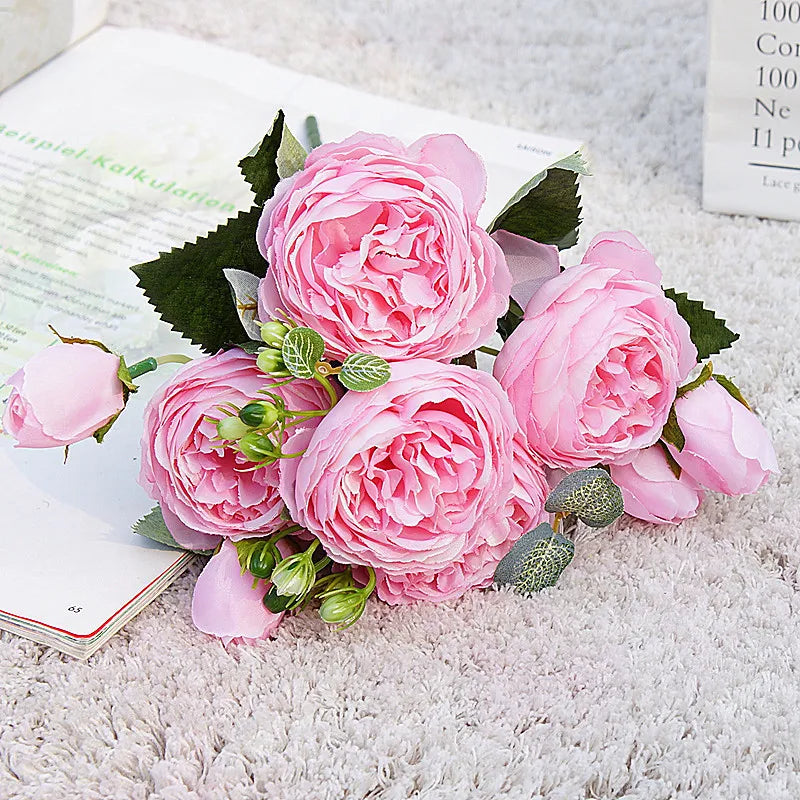 A bouquet of pink silk rose and peony artificial flowers displayed on a white surface.