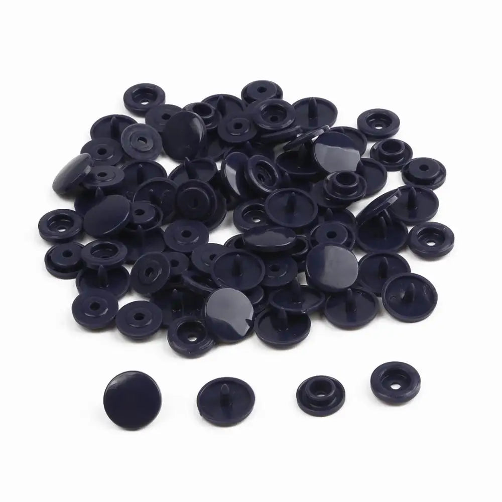 A pile of assorted black snap buttons, measuring 12mm and 10.5mm, for crafting.