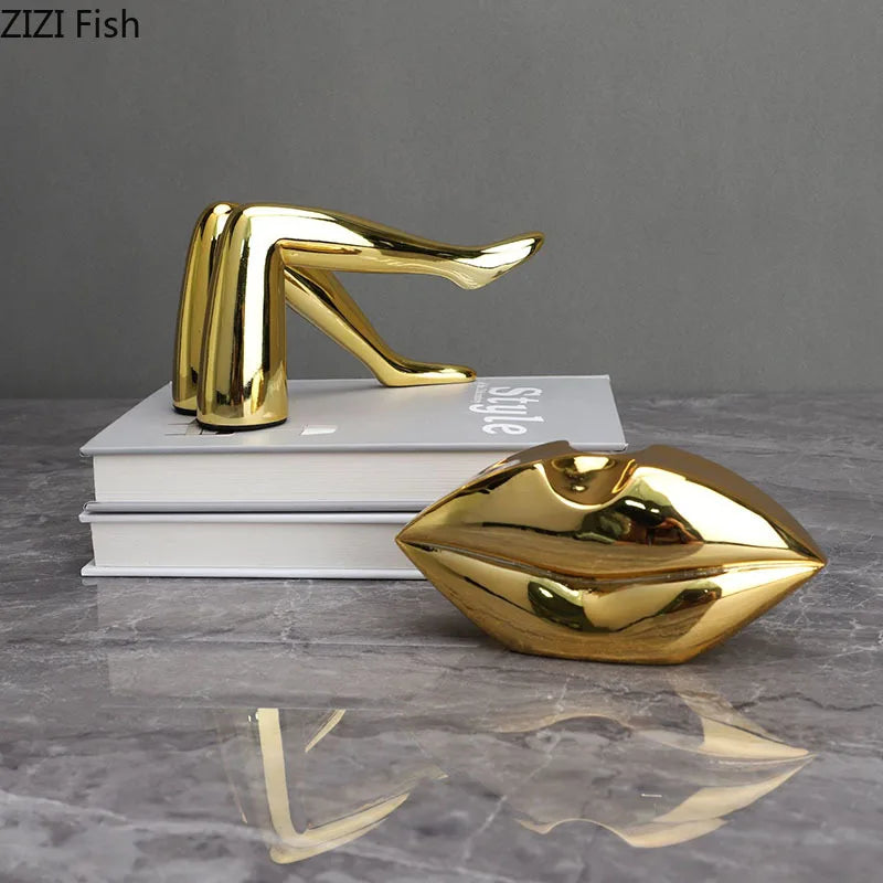 A gold faux finish sculpture of a human body, resembling lips or a face, resting on a stack of white books.