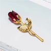A gold-toned crystal rose artificial flower with a deep red bloom and leaves.