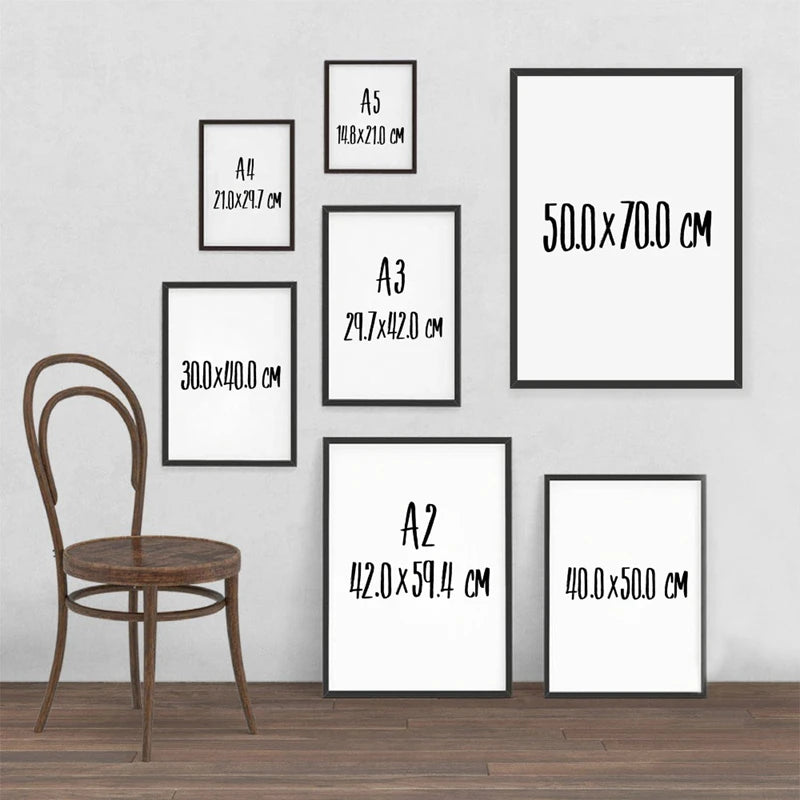 Galeriewand mit schwarz-weißen Kunstprints unterschiedlicher Größe an einer grauen Wand.