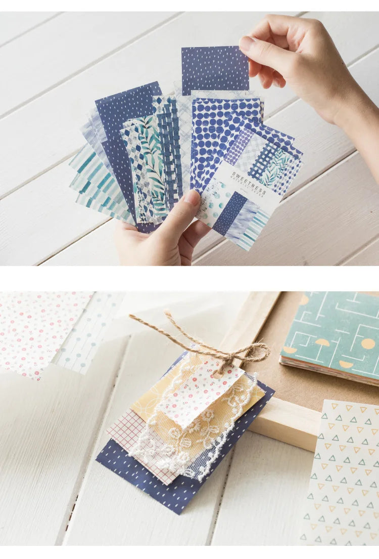 A collection of decorative paper products including memo pads and cards in various blues, greens, and pinks.