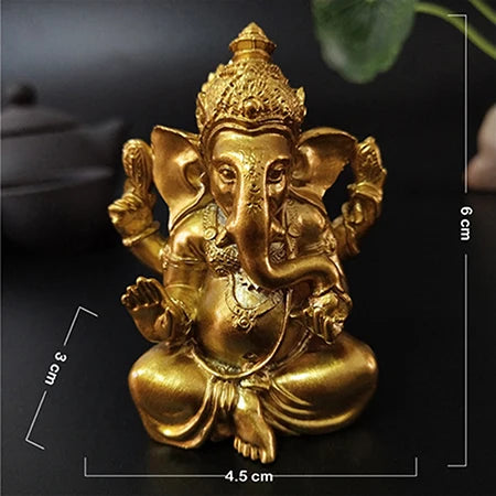 Gold Ganesha statue handcrafted resin figurine sitting on a dark surface.