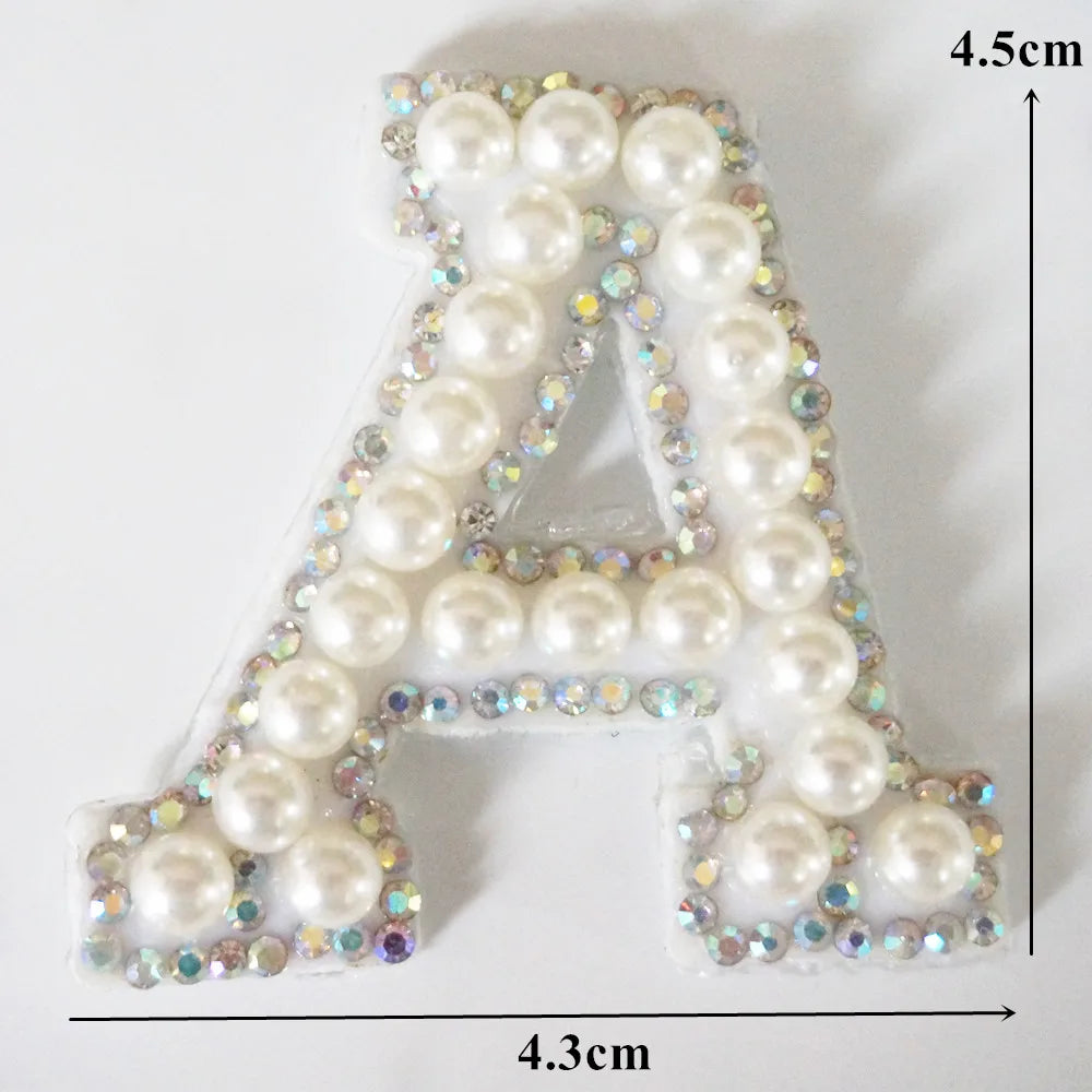 A alphabet letter patch made of white pearls and iridescent rhinestones