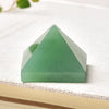 Cristal piramidal de fluorita natural verde claro y liso sobre una superficie blanca texturizada.