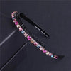 A black crystal rhinestone headband with colorful stones is displayed on a dark surface.