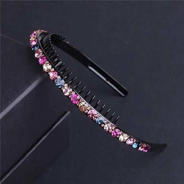 A black crystal rhinestone headband with colorful stones is displayed on a dark surface.