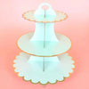 A three-tier cardboard cupcake stand with a light blue color and gold trim.