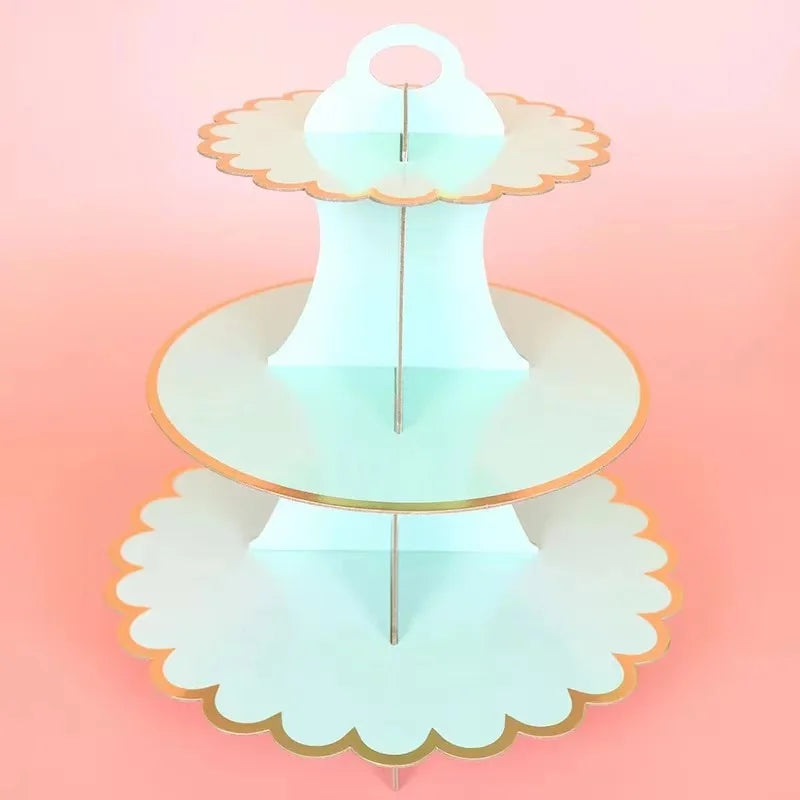 A three-tier cardboard cupcake stand with a light blue color and gold trim.