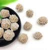 Small, round, natural desert rose selenite stones scattered on a black plate.