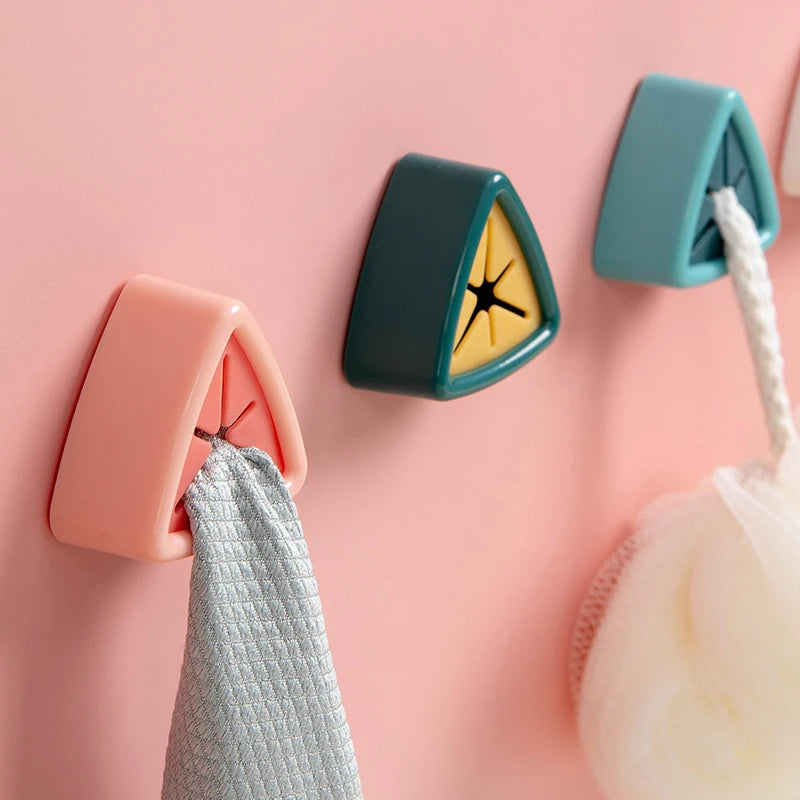 Pink and teal suction cup towel holders mounted on a wall, with a gray towel hanging from one.