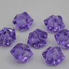 A collection of purple acrylic crystal decorations for parties scattered on a light gray surface.