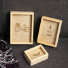 A set of three vintage wooden photo frames featuring botanical and bicycle illustrations on a dark gray background.