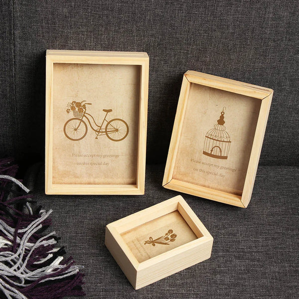 A set of three vintage wooden photo frames featuring botanical and bicycle illustrations on a dark gray background.
