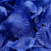 A close-up of deep blue silk rose petals scattered on a dark surface.