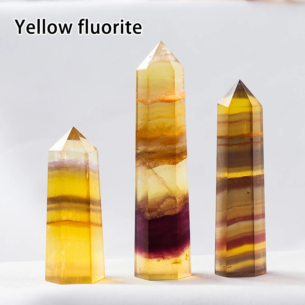 Three yellow fluorite crystal points of varying sizes and colors displayed on a white surface.