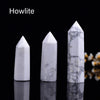 A white natural crystal point prism tower displayed against a black reflective surface.
