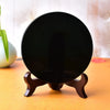 A natural black obsidian mirror resting on a wooden stand.