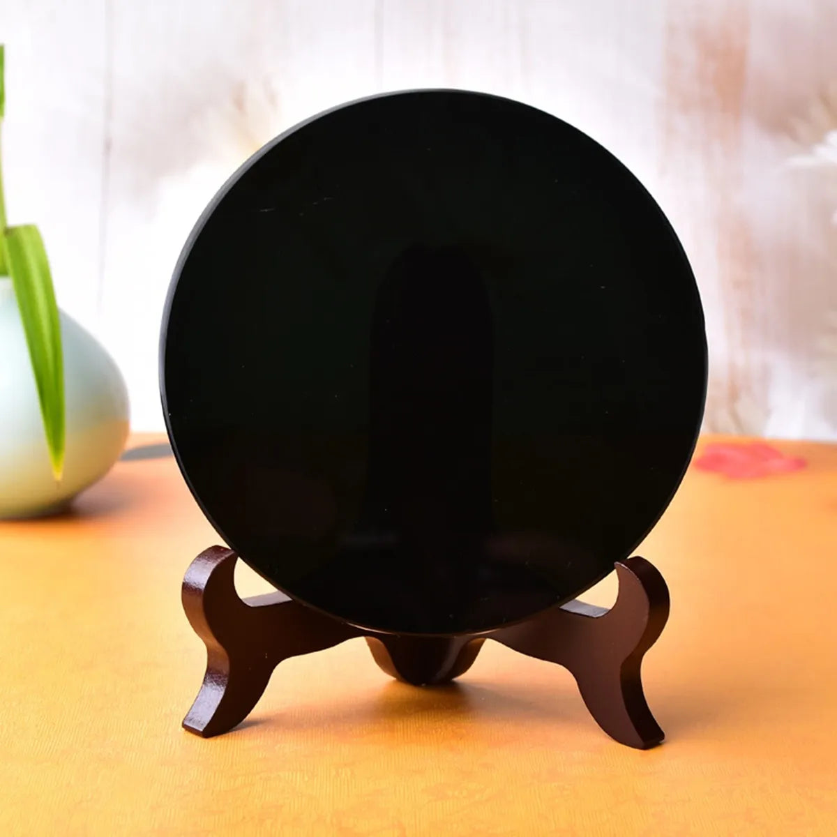 A natural black obsidian mirror resting on a wooden stand.