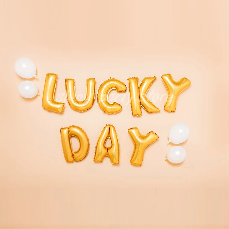 Gold foil letter balloons spelling LUCKY DAY with white balloons on a light background