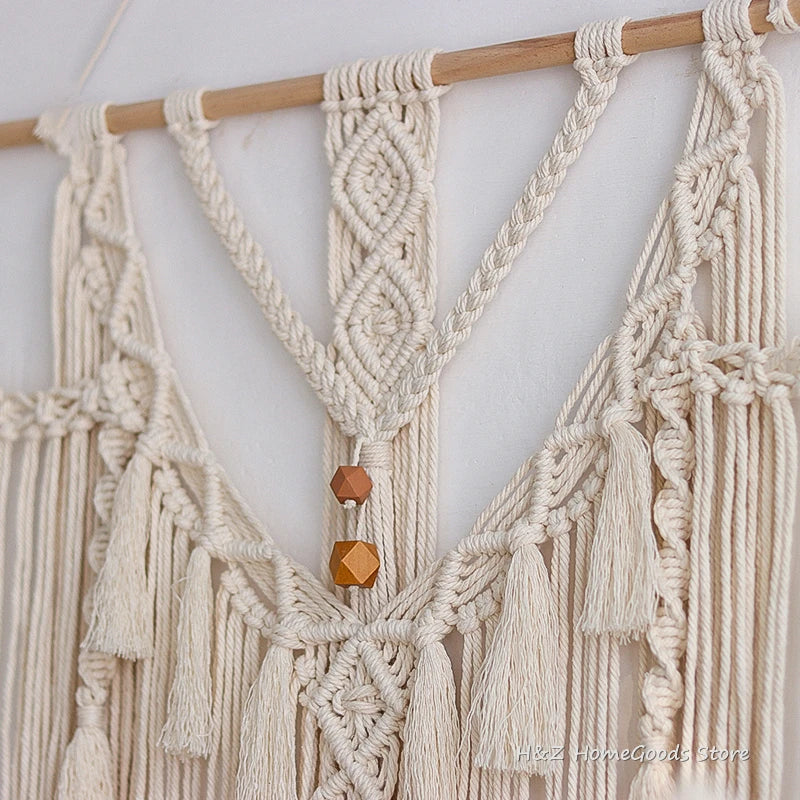 Cream macrame wall hanging tapestry featuring knotted cords and wooden beads