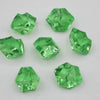 A collection of faceted green acrylic crystals, cut in various geometric shapes, displayed on a white surface.