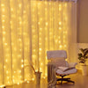 Warm white LED curtain lights illuminating a room with a white armchair and potted plant.