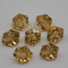 Several faceted yellow acrylic crystal decorations shaped like pyramids are displayed on a white surface.