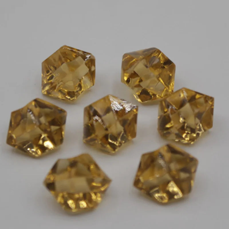 Several faceted yellow acrylic crystal decorations shaped like pyramids are displayed on a white surface.