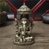 Bronze Ganesha Buddha statue with a conical crown sitting on a wooden surface.