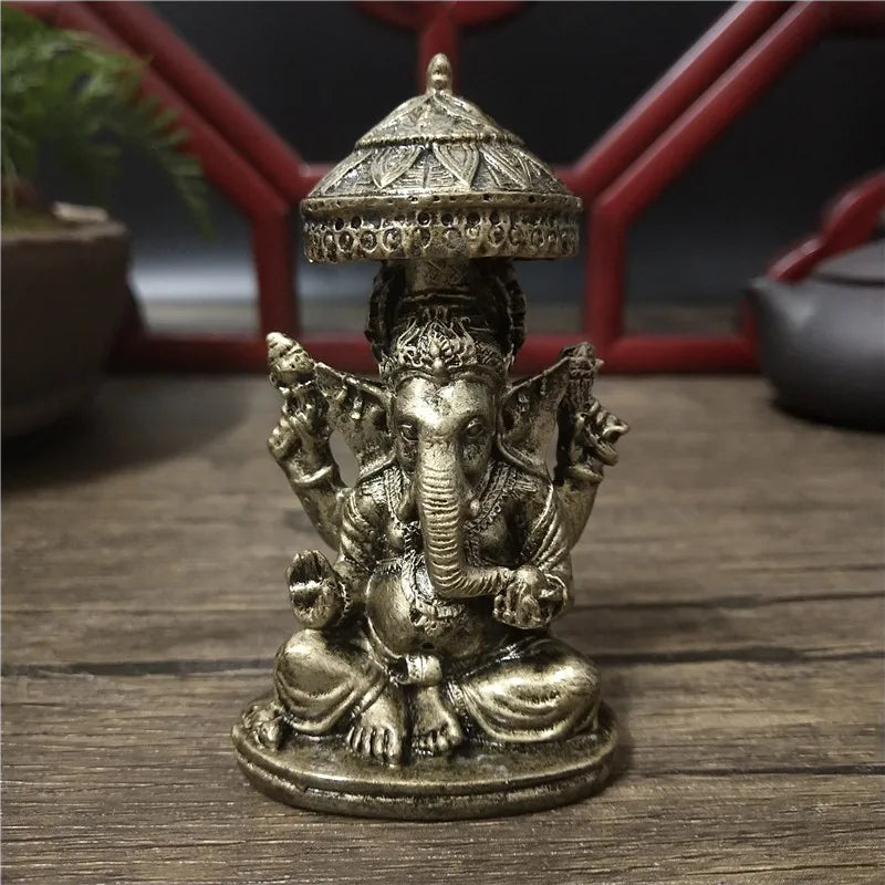 Bronze Ganesha Buddha statue with a conical crown sitting on a wooden surface.