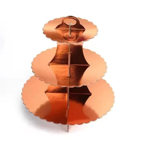 A three-tier cardboard cupcake stand in a metallic copper or rose gold color.